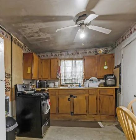 a kitchen with stainless steel appliances a sink a stove a refrigerator cabinets and furniture