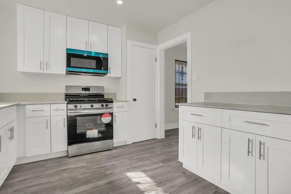 a kitchen with stainless steel appliances a white stove top oven and white cabinets