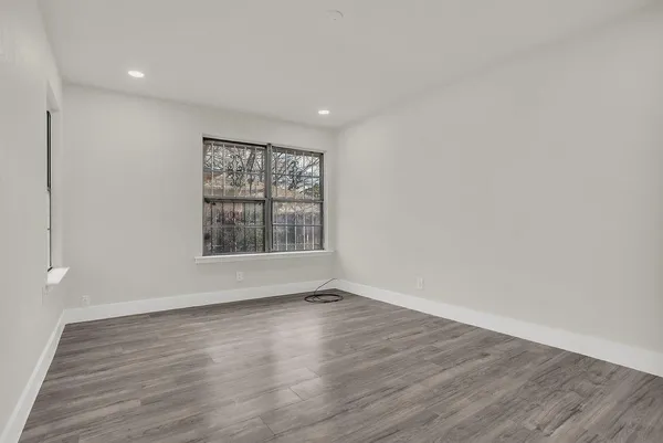 a view of an empty room with wooden floor and a window