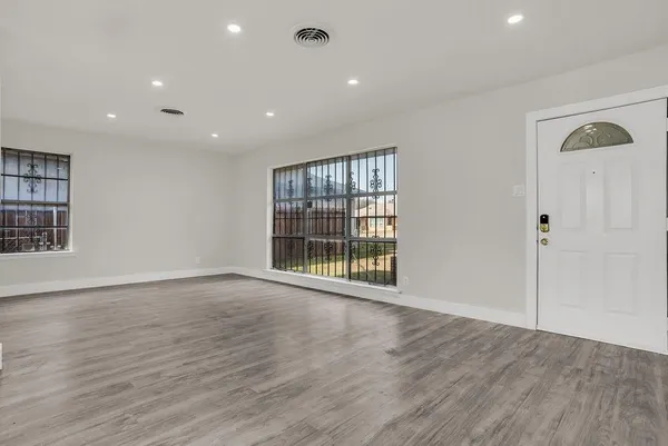 a view of an empty room with wooden floor and a window