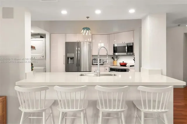 a kitchen with stainless steel appliances kitchen island granite countertop a sink and a refrigerator