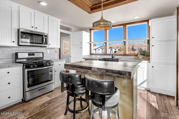 a kitchen with stainless steel appliances granite countertop a stove a sink dishwasher and a refrigerator with wooden floor