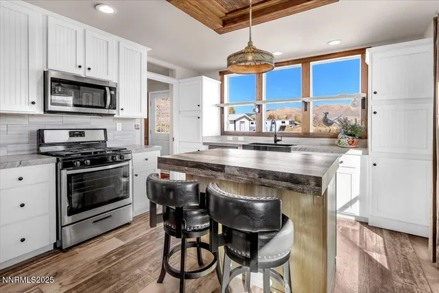 a kitchen with stainless steel appliances granite countertop a stove a sink dishwasher and a refrigerator with wooden floor