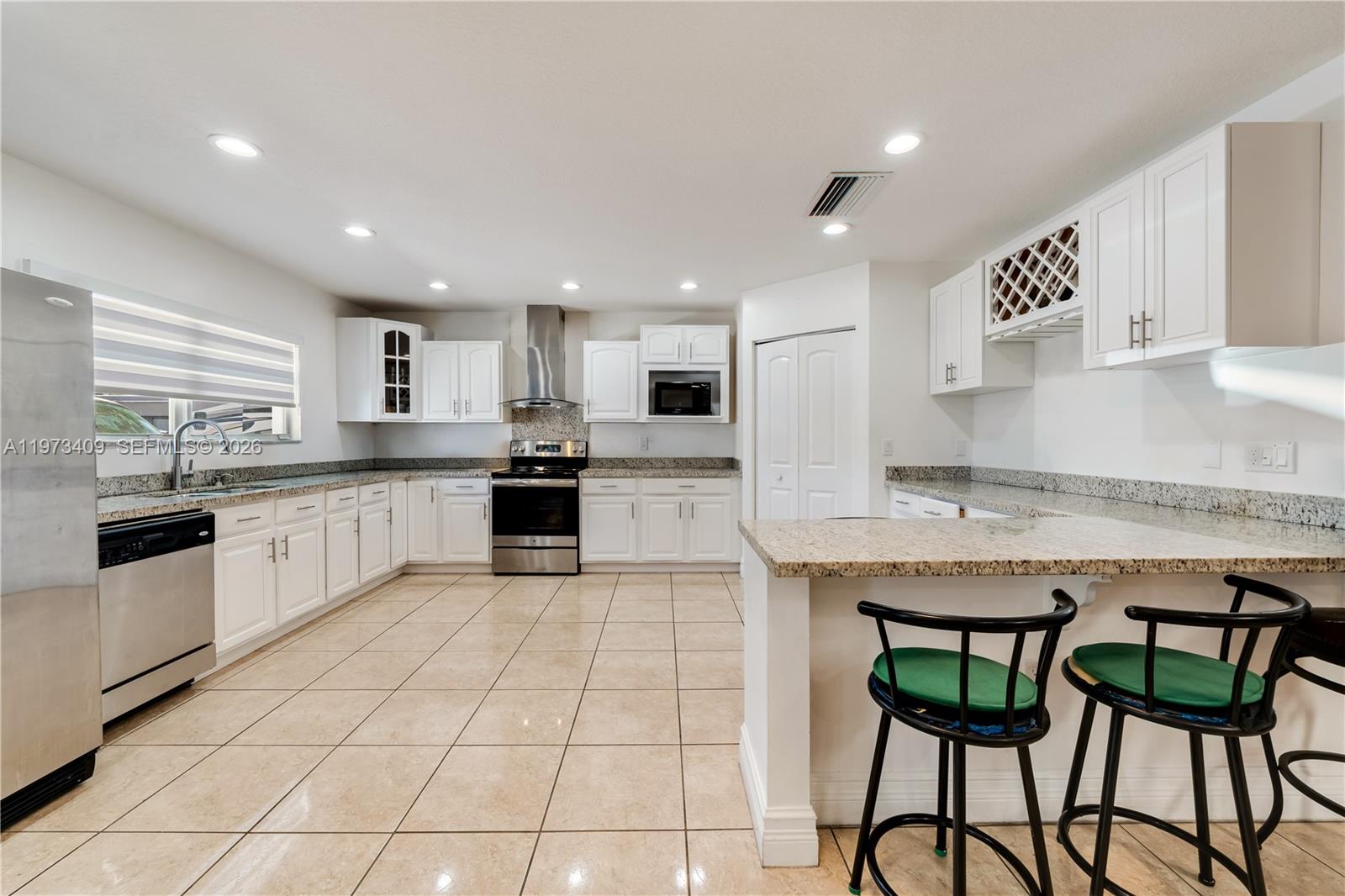 13050 Southwest 26th Street Miami, FL 33175 - Photo 23 of 43 a large kitchen with stainless steel appliances granite countertop a stove a sink a microwave and a refrigerator