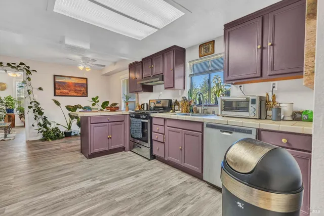 a kitchen with stainless steel appliances granite countertop a stove a sink dishwasher and cabinets with wooden floor