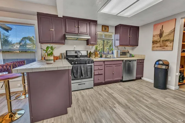 a kitchen with stainless steel appliances granite countertop a stove top oven a sink dishwasher and cabinets with wooden floor