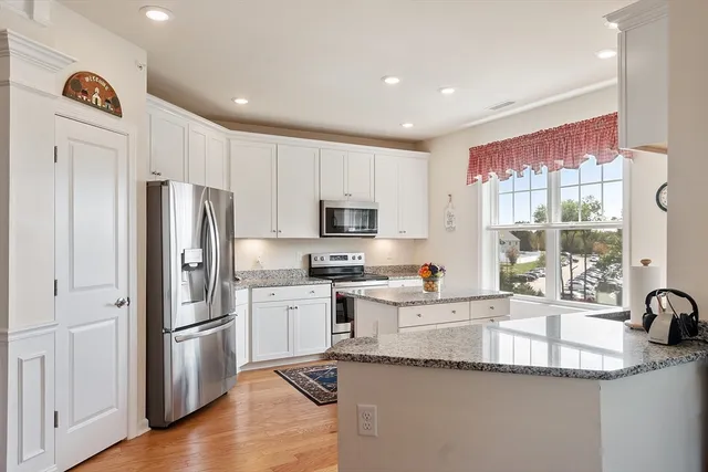 a kitchen with granite countertop stainless steel appliances a refrigerator a sink a stove and cabinets