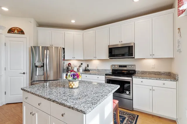 a kitchen with stainless steel appliances granite countertop a sink dishwasher a refrigerator and white cabinets