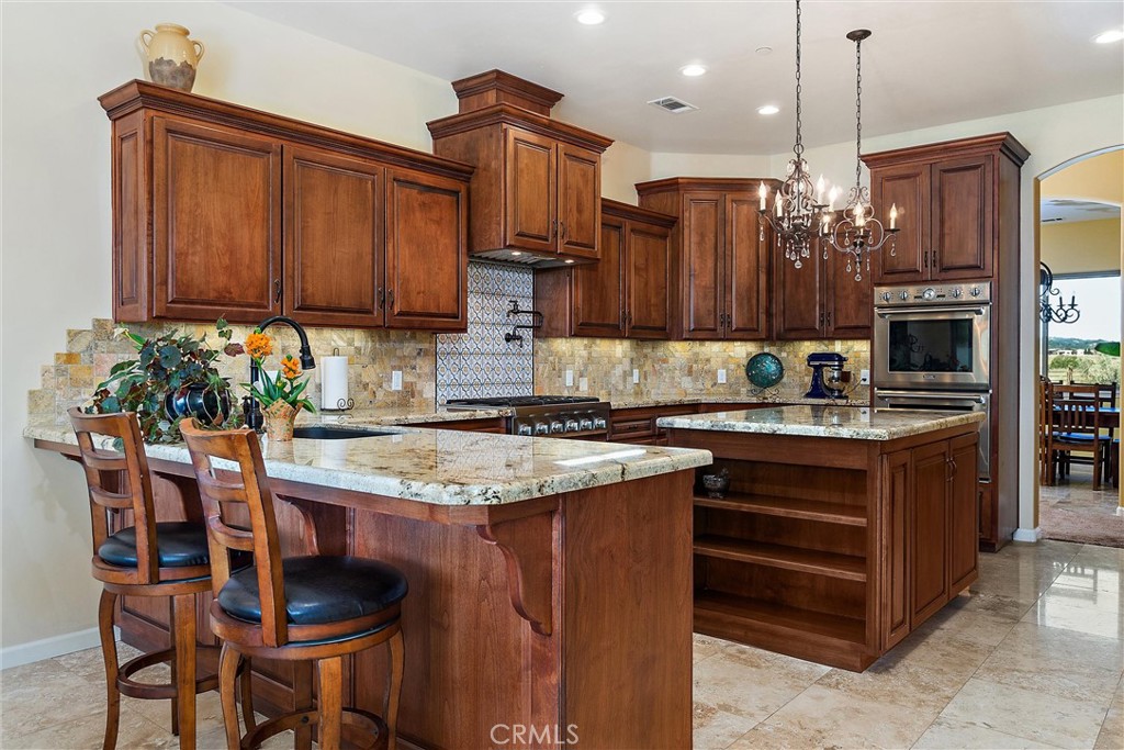 18205 Walnut Avenue Atascadero, CA 93422 - Photo 10 of 46 a kitchen with granite countertop a table chairs stove and cabinets