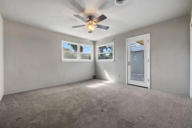 an empty room with windows and chandelier fan