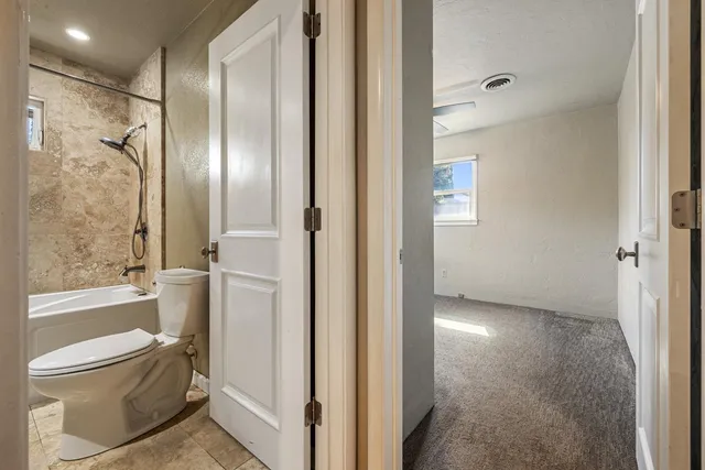 a bathroom with a granite countertop bathtub shower sink vanity and toilet