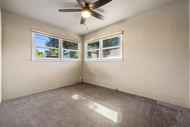 an empty room with a window and a fan