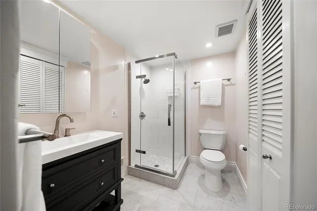 a bathroom with a toilet a sink a mirror and a shower