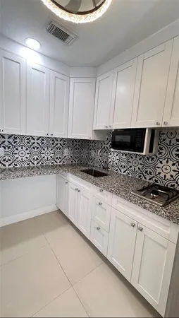 a kitchen with granite countertop white cabinets and white appliances