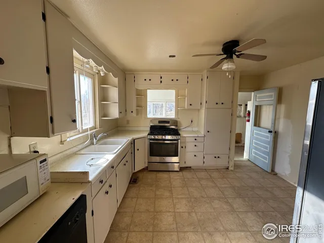 a large white kitchen with a stove a sink a refrigerator and a counter top space