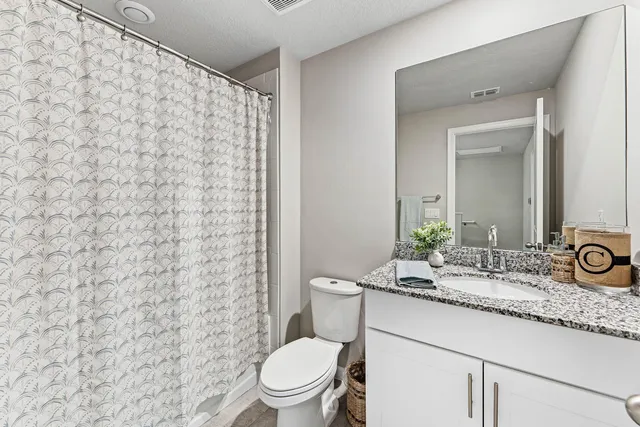 a bathroom with a granite countertop toilet sink and mirror