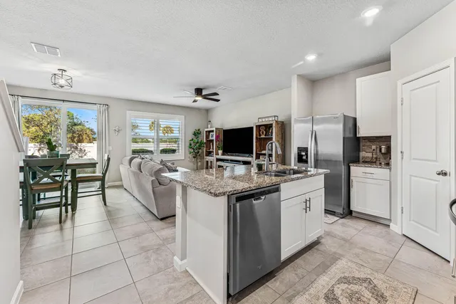 a kitchen with stainless steel appliances granite countertop a stove top oven a refrigerator a sink dishwasher with a dining table and chairs with wooden floor