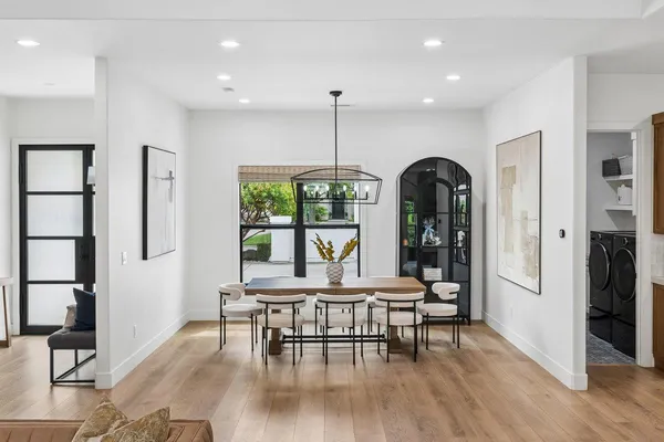 a kitchen with stainless steel appliances kitchen island granite countertop a stove a sink a dining table and chairs with wooden floor