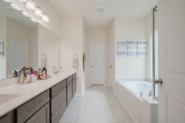 a spacious en suite bathroom with a tub sink a mirror and a shower