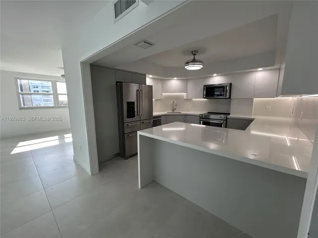 a large kitchen with kitchen island a sink stainless steel appliances and cabinets