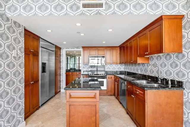 a kitchen with stainless steel appliances granite countertop a stove a sink and a refrigerator