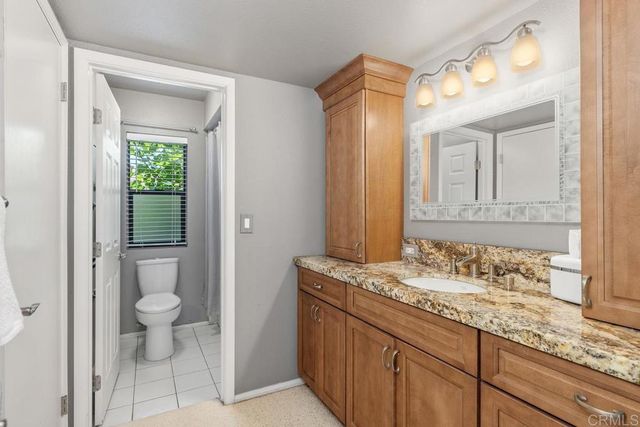 a bathroom with a granite countertop sink a toilet and a mirror