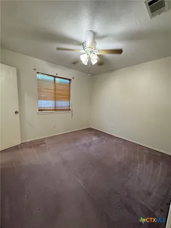 an empty room with a chandelier fan and windows