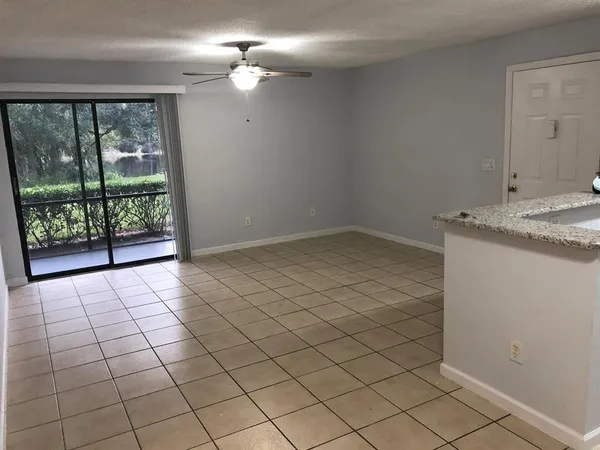 a view of an empty room and window & chandelier fan