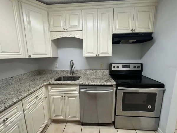 a kitchen with granite countertop white cabinets and a stove top oven