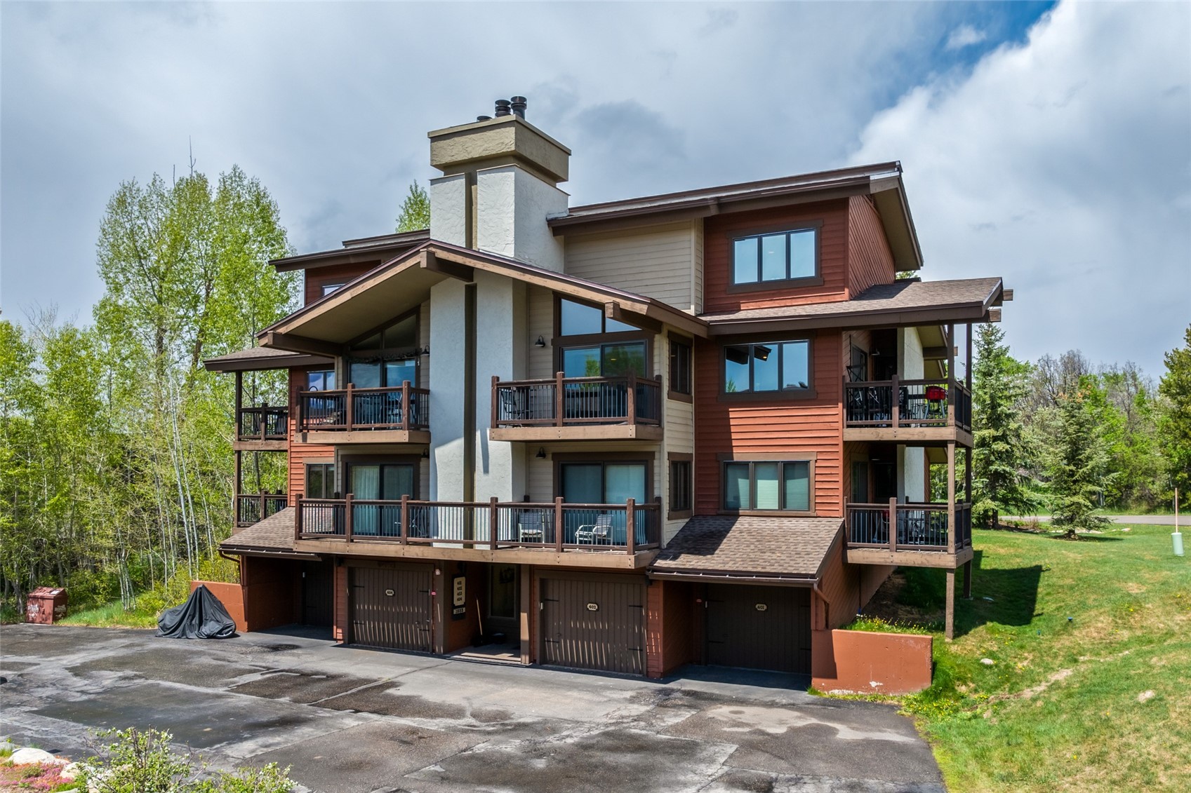 1655 Ranch Road, Unit 403 Steamboat Springs, CO 80487 - Photo 2 of 36 Back of property with a balcony, a chimney, a yard, driveway, and a garage