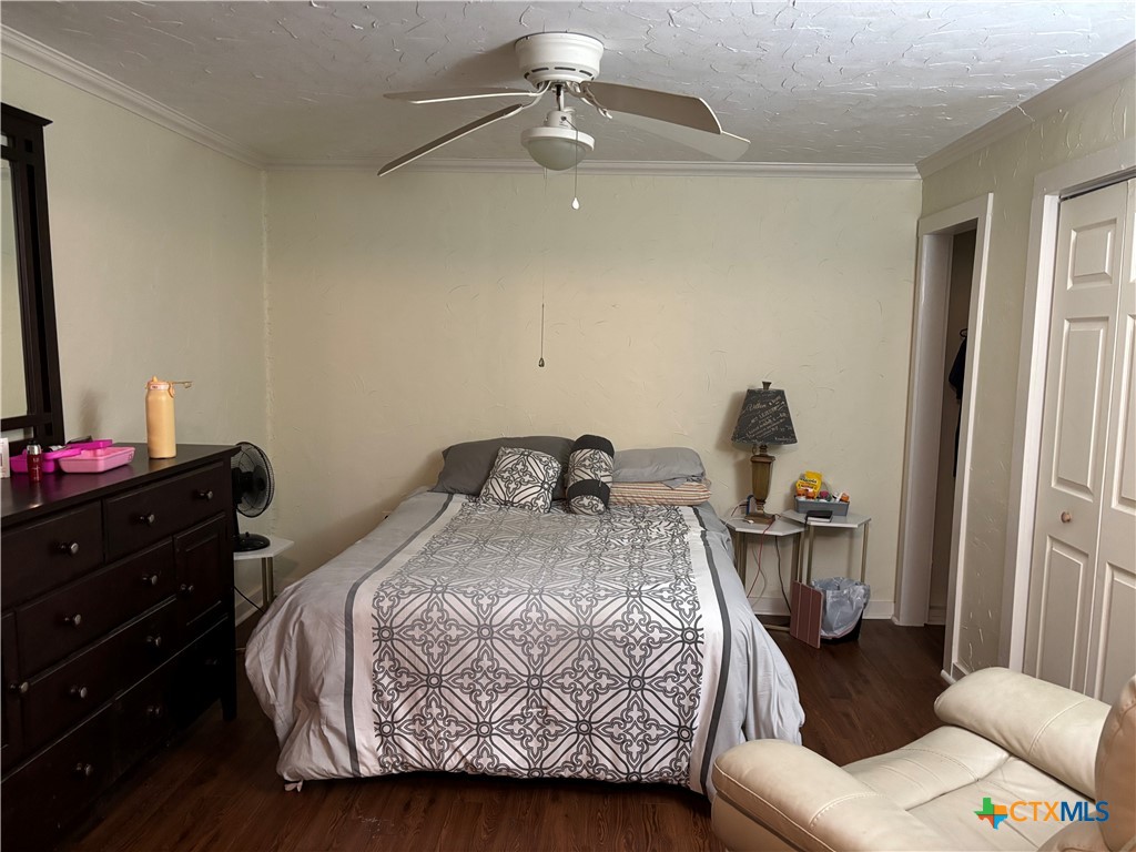 613 East Broadway Street, Unit 5 Cuero, TX 77954 - Photo 17 of 34 a bedroom with a bed and wooden floor