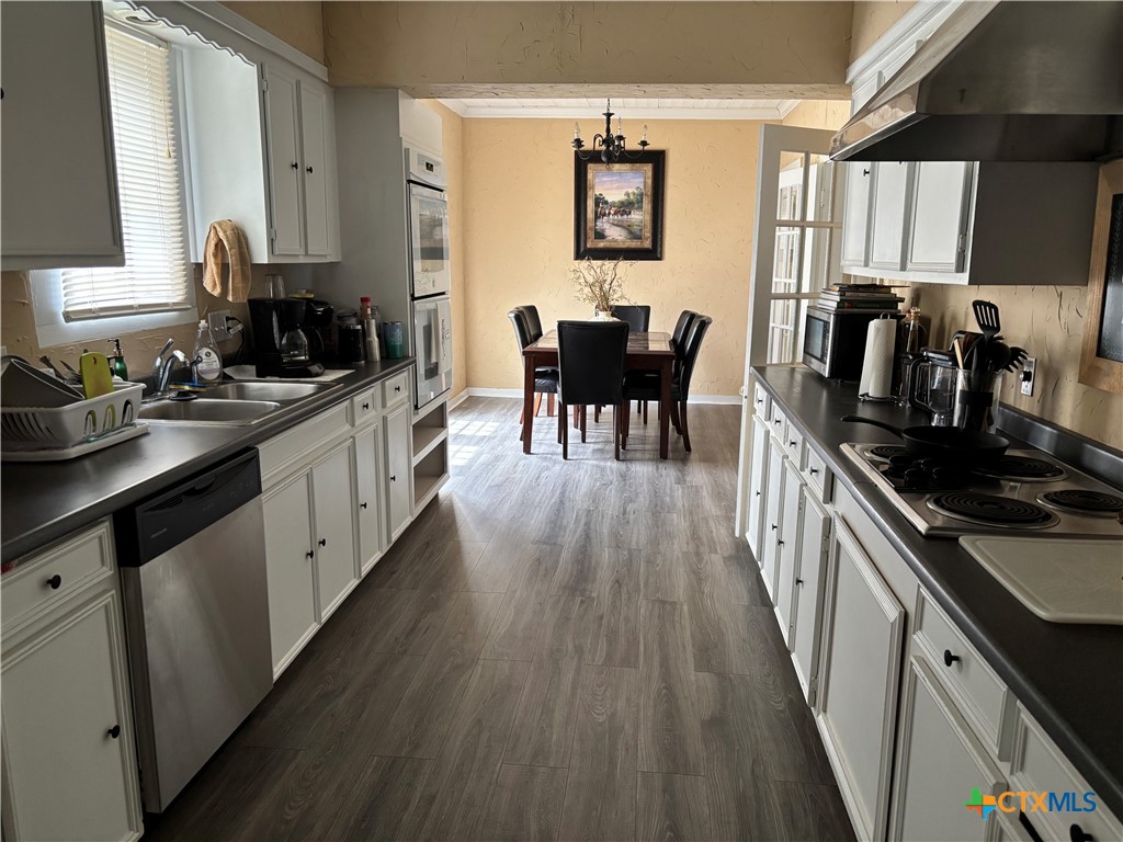 613 East Broadway Street, Unit 5 Cuero, TX 77954 - Photo 9 of 34 a kitchen with granite countertop kitchen island wooden floors and stainless steel appliances