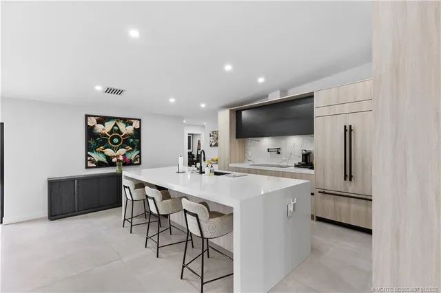 a kitchen with stainless steel appliances a sink a stove a refrigerator with white cabinets and wooden floor