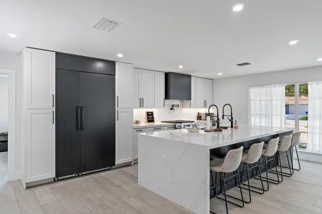 a kitchen with stainless steel appliances granite countertop a dining table chairs refrigerator and cabinets