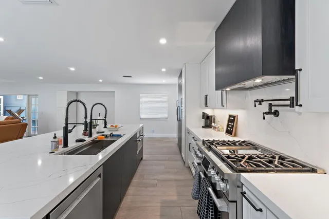 a kitchen with stainless steel appliances a sink a stove and cabinets