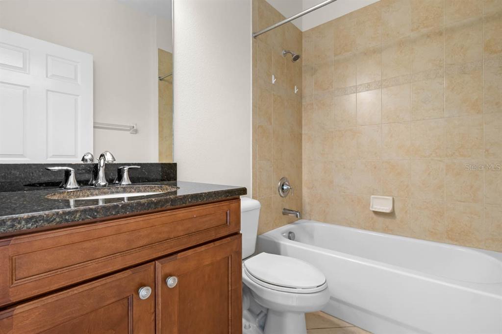 16252 Amethyst Key Drive Wimauma, FL 33598 - Photo 25 of 47 a bathroom with a granite countertop sink a toilet a mirror and bathtub
