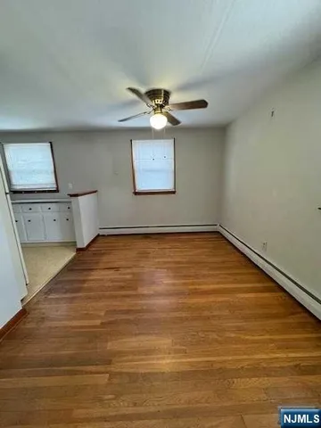 a view of a room with wooden floor and a ceiling fan