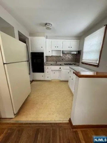 a kitchen with a sink a stove top oven a refrigerator and white cabinets
