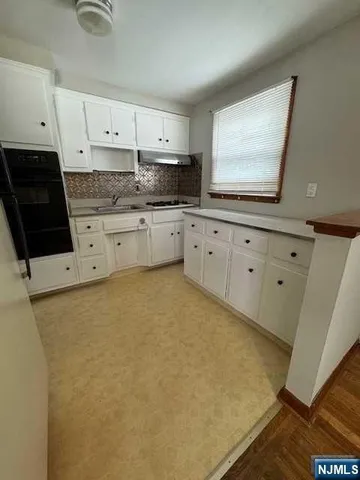 a kitchen with granite countertop white cabinets and black appliances