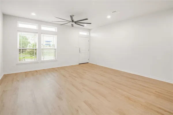 an empty room with windows and fan