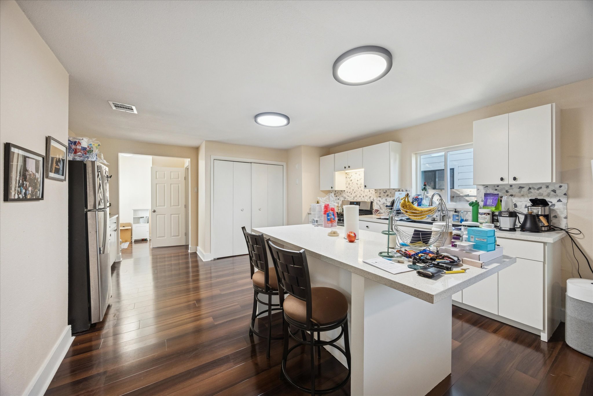 907 East 53rd Street Austin, TX 78751 - Photo 7 of 30 Kitchen with light countertops, white cabinets, freestanding refrigerator, a center island, and a kitchen breakfast bar