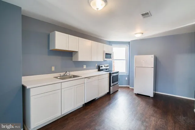 a kitchen with a sink stainless steel appliances and white cabinets