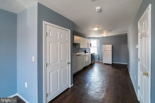 a view of a kitchen with refrigerator and wooden floor