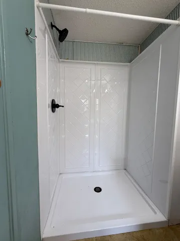a view of an empty room with wooden floor and a ceiling fan