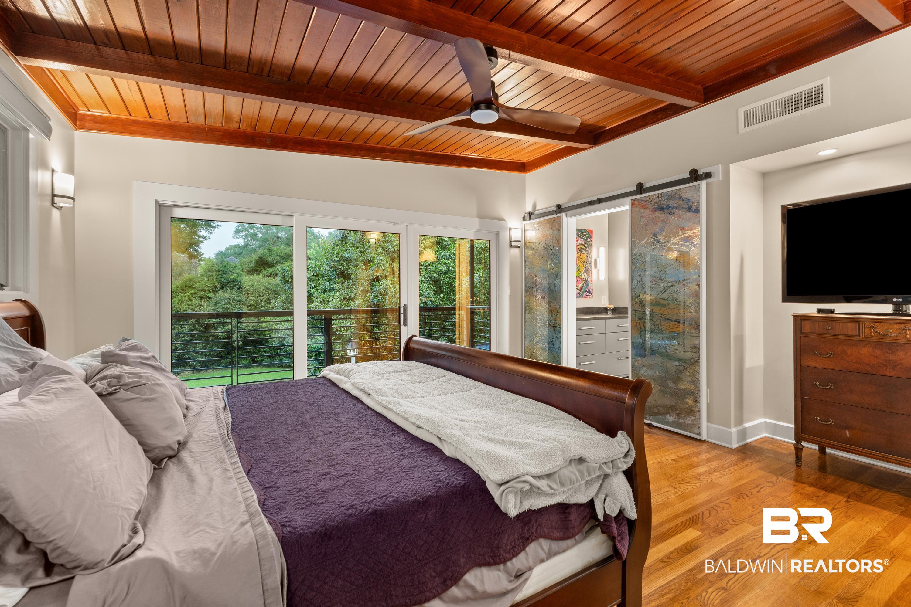 233 Suzanne Circle Mobile, AL 36608 - Photo 20 of 85 Bedroom with a barn door, wood finished floors, a wooden ceiling with exposed beams, access to outside, and ceiling fan