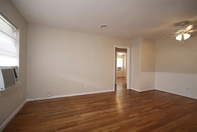 a view of an empty room with wooden floor and a window