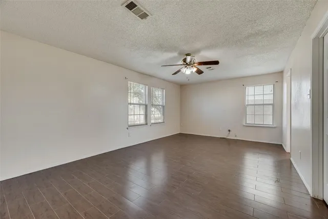 a view of an empty room with a window and wooden floor