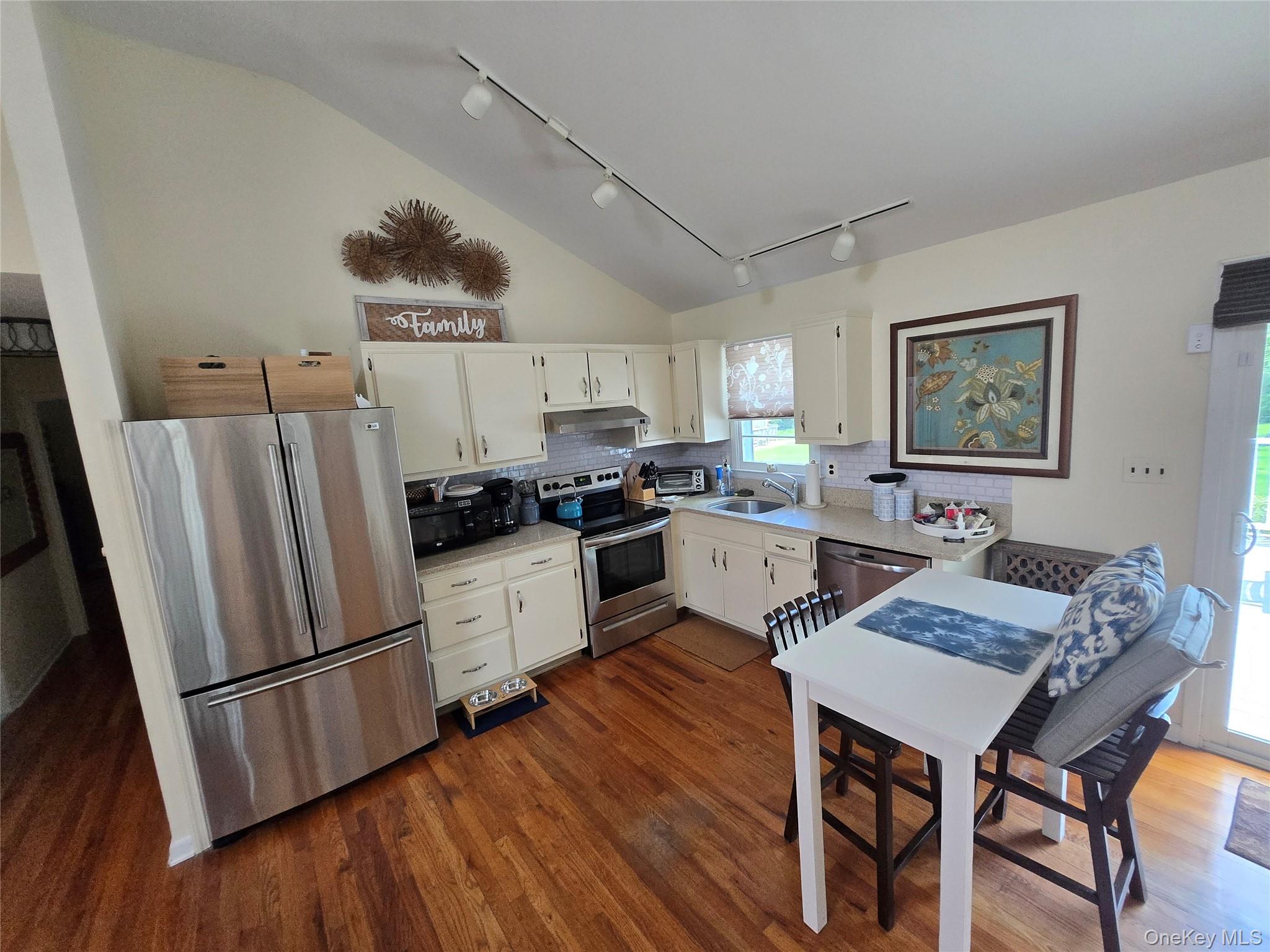 870 Noyack Road Southampton, NY 11968 - Photo 8 of 19 a kitchen with stainless steel appliances a refrigerator a stove a sink dishwasher and white cabinets with wooden floor
