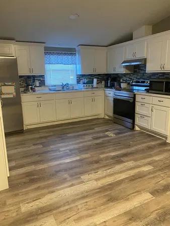 a kitchen with stainless steel appliances granite countertop a stove a sink and white cabinets