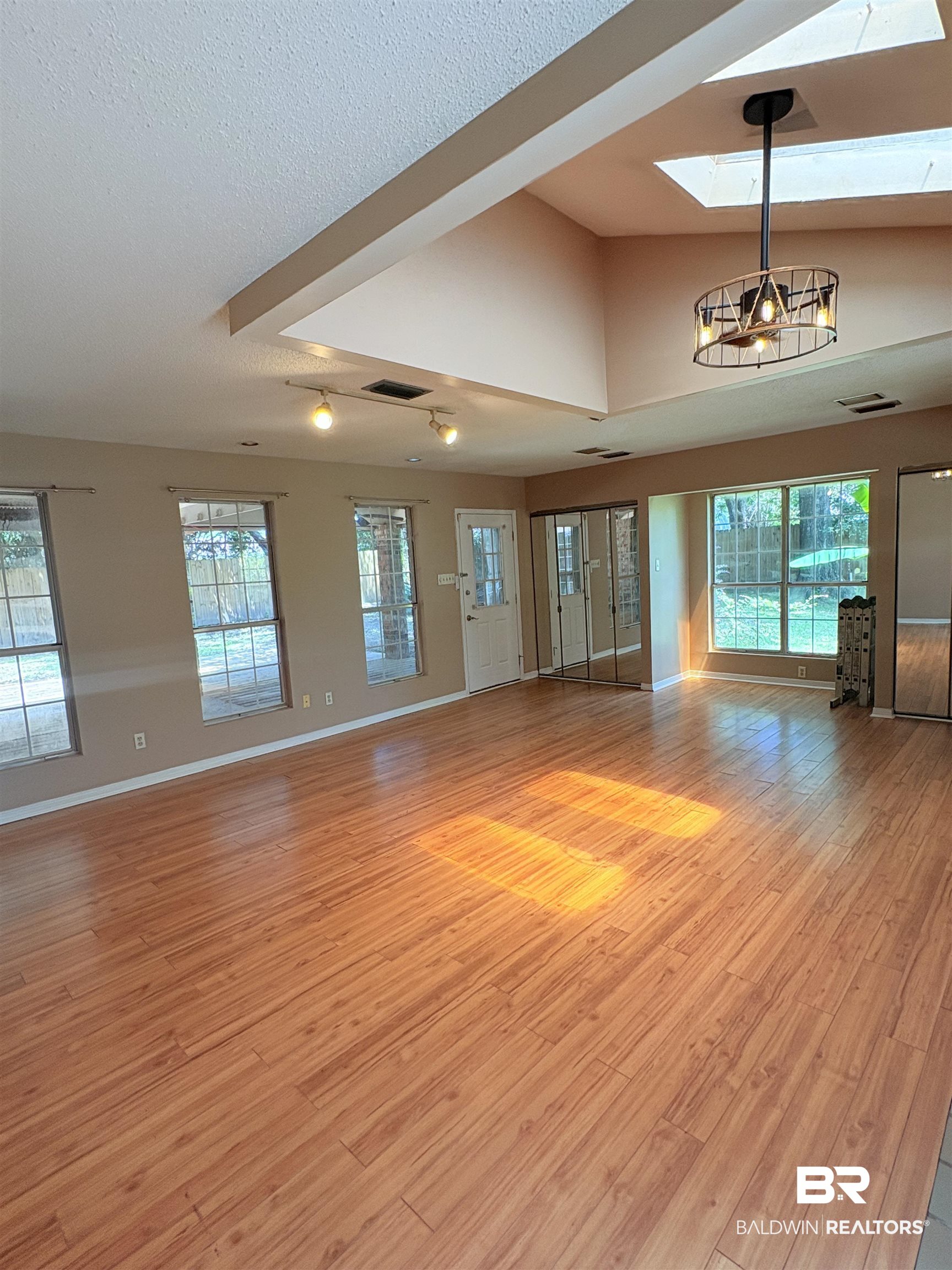 8070 Middle Ring Road Mobile, AL 36619 - Photo 3 of 26 Unfurnished living room featuring a skylight, light wood finished floors, plenty of natural light, and a textured ceiling